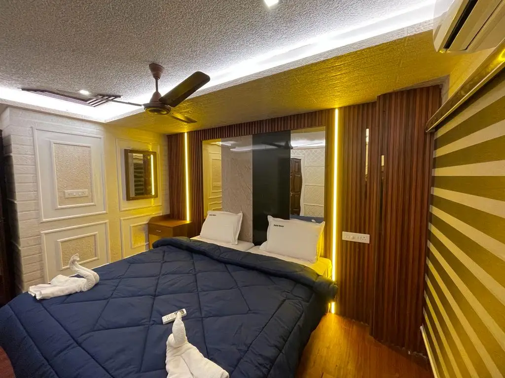 Bedroom with navy bedding, ceiling fan and mirrored wall on a Kerala houseboat