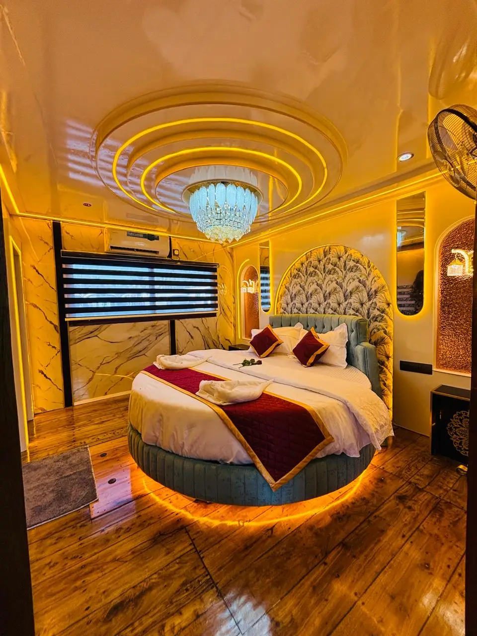 Round bed beneath a crystal chandelier in a luxury Alleppey houseboat bedroom
