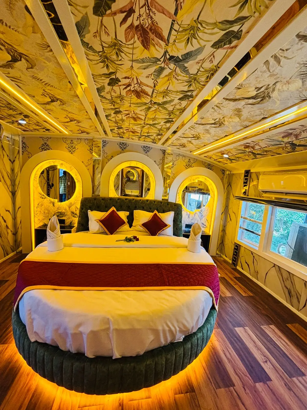 Luxury houseboat bedroom with a round bed, floral ceiling mural and arched mirrors