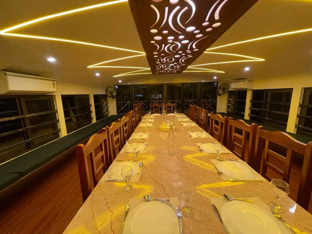 Long dining table laid with full place settings on a large Alleppey houseboat
