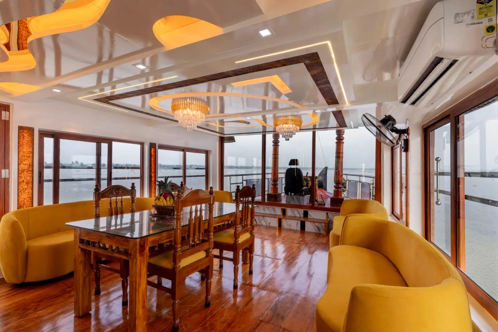 Dining table set beside panoramic lake windows on a two-bedroom houseboat