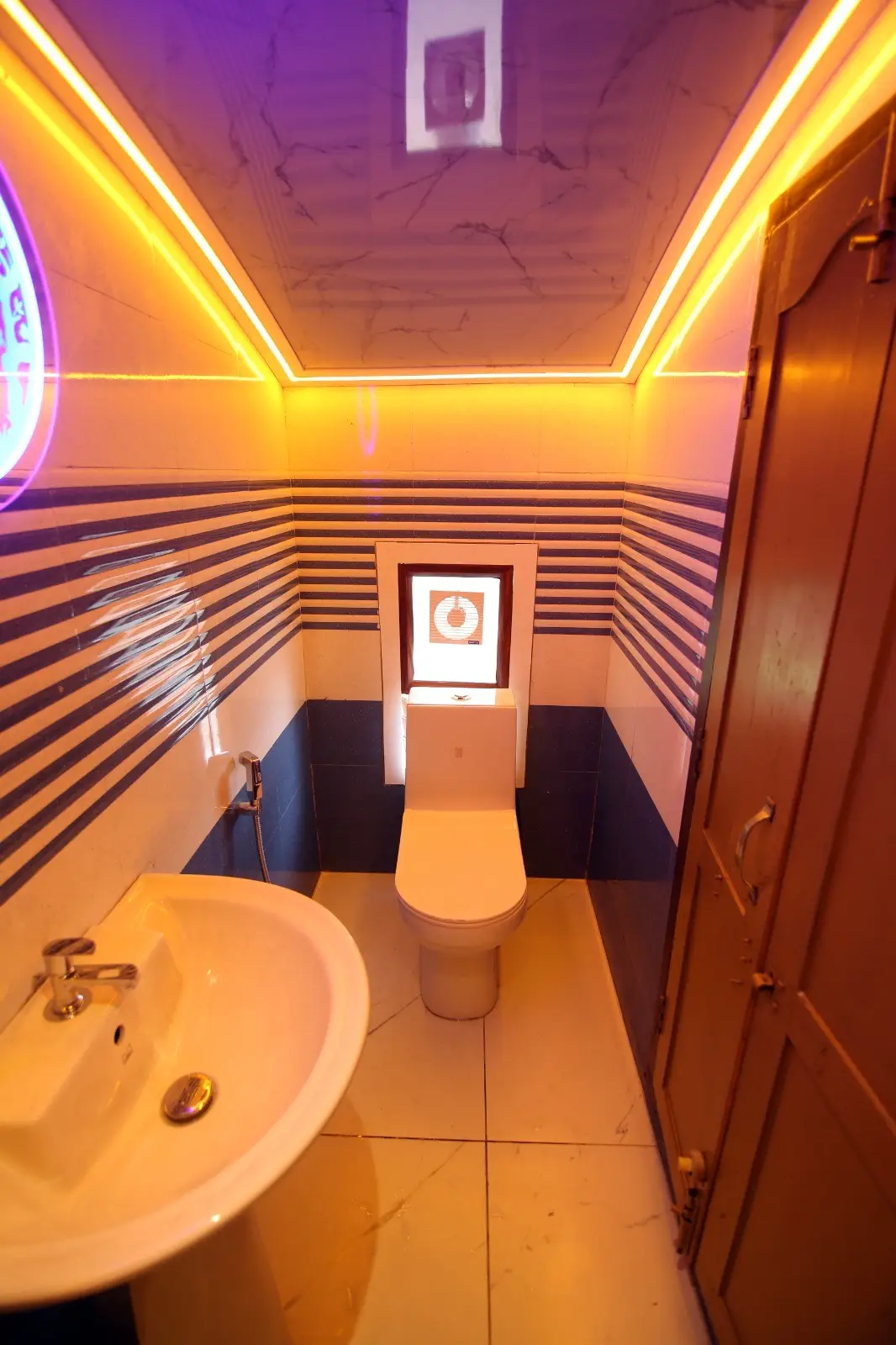 Mood-lit en-suite bathroom with striped marble tiling on a Kerala houseboat