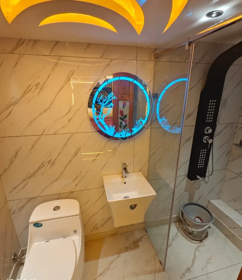 En-suite bathroom with marble tiling, backlit mirror and glass shower cubicle