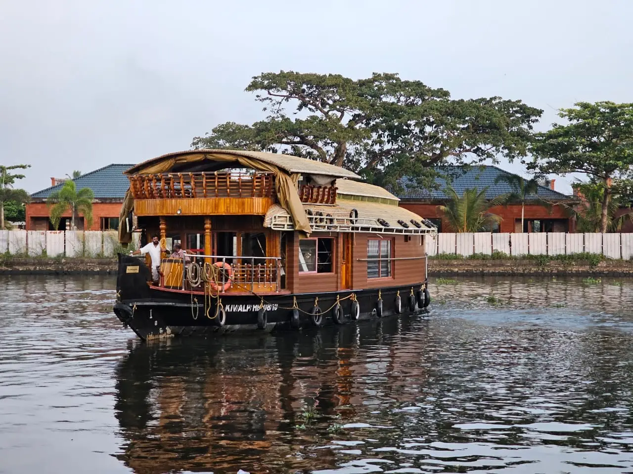 One-bedroom premium Alleppey houseboat with upper deck cruising a backwater canal