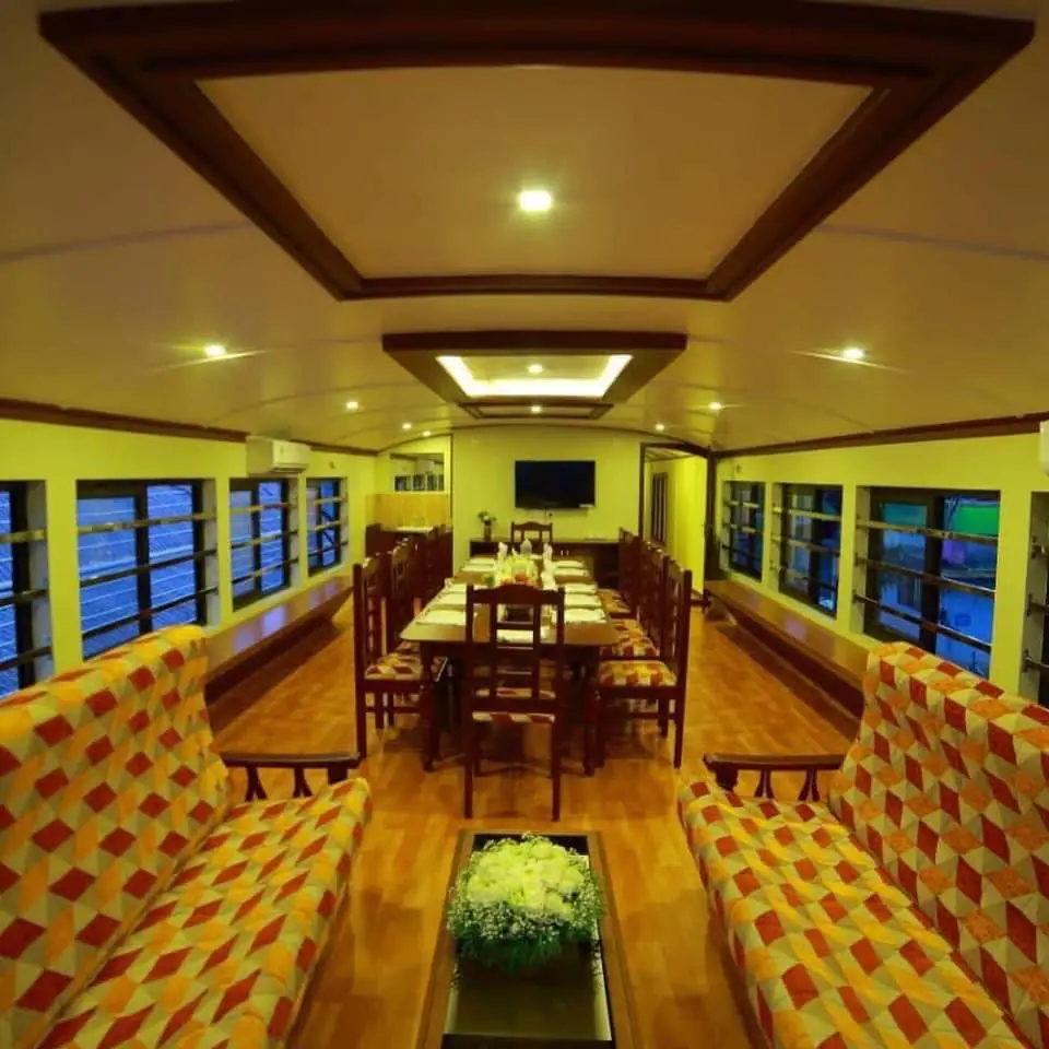 Lounge and dining area with patterned sofas on a six-bedroom Kerala houseboat