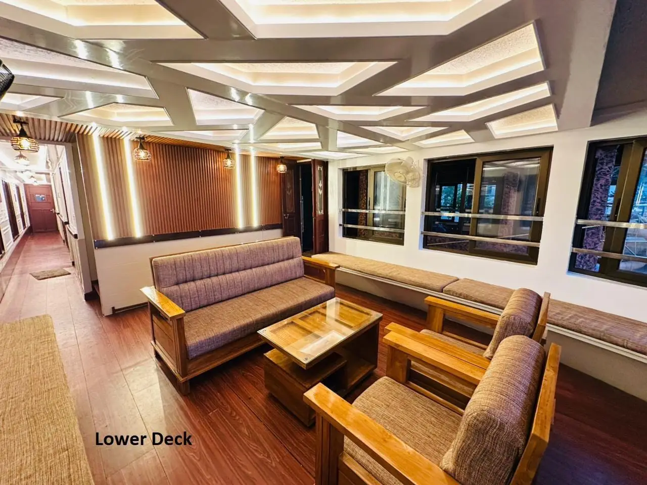 Lower deck lounge with sofas and coffee table under a coffered lit ceiling