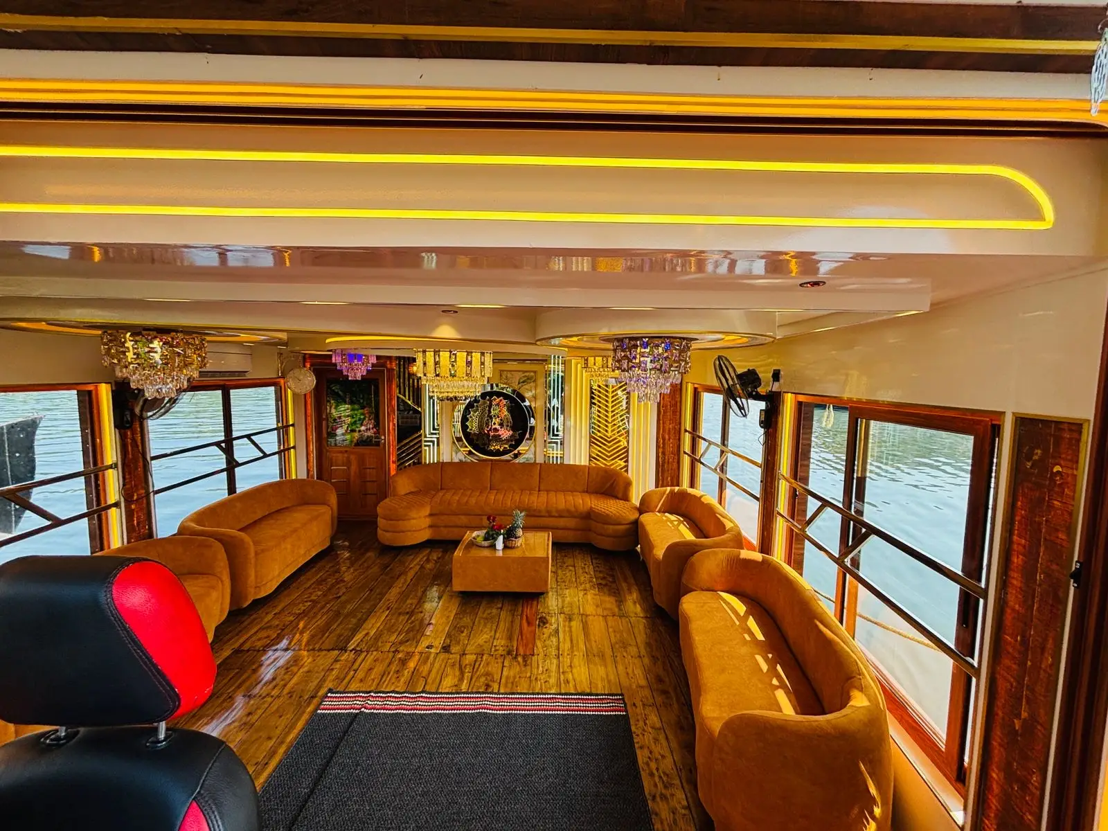 Lower deck lounge with tan sofas and chandeliers on a luxury Alleppey houseboat