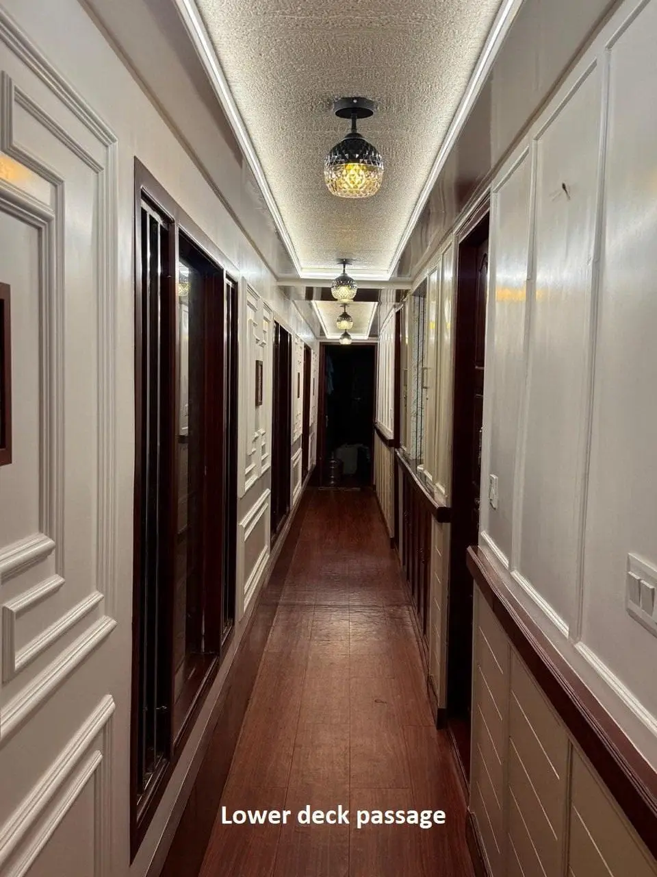 Panelled lower deck passage lined with bedroom doors on a Kerala houseboat