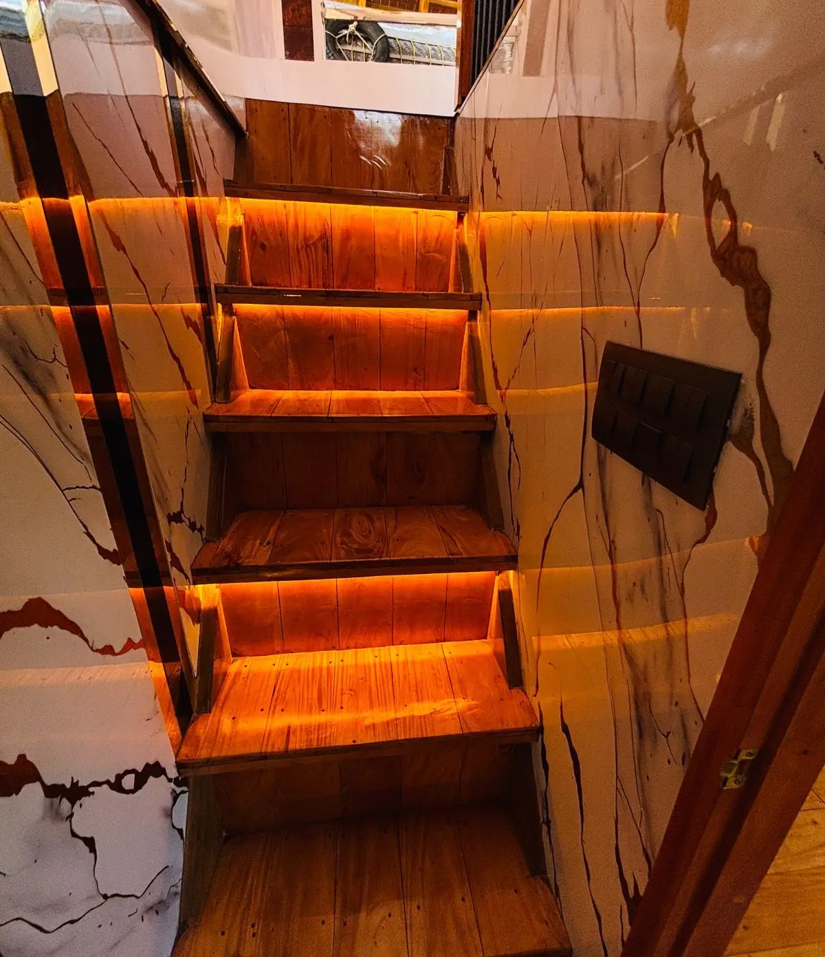 Backlit timber staircase leading to the upper deck of a Kerala houseboat