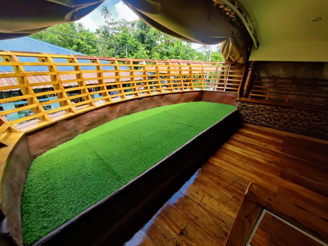 Upper sundeck with artificial lawn seating and painted rails on a Kerala houseboat