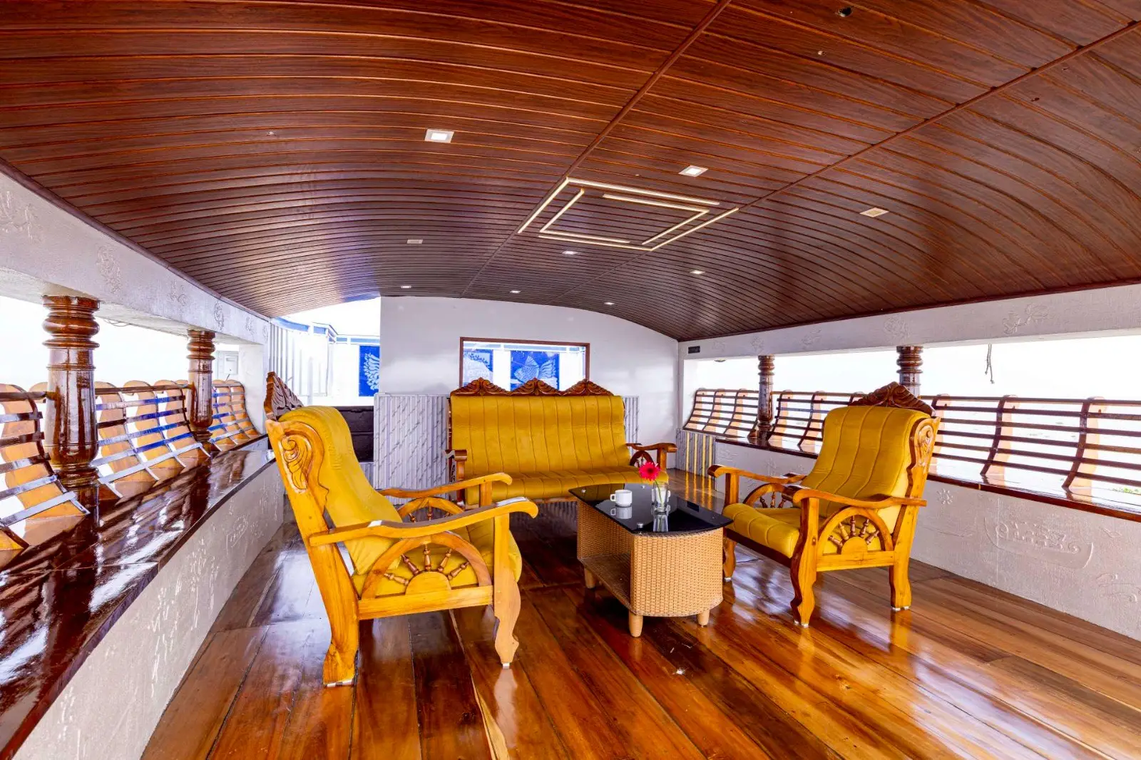 Wood-panelled upper deck seating lounge on a premium Kerala houseboat